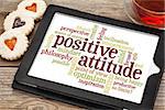 positive attitude word cloud on a digital tablet with a cup of tea and heart cookies