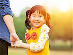 pretty girl hold father hand  in the park with sunlight