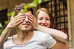 Young woman covering boyfriend's eyes