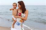 Pregnant woman holding toddler on beach