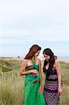 Pregnant woman and friend standing in field