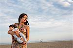Mother standing on beach holding baby