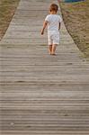 Rear view of toddler walking along boardwalk