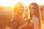 Woman and teenager standing in field at dusk holding domestic dog