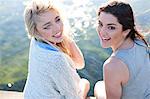 Two female friends sitting on pier