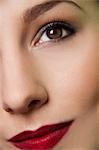 Cropped studio portrait of young woman's eye and lips