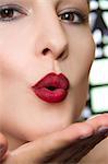 Cropped studio portrait of young woman blowing a kiss