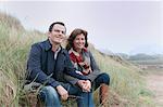 Couple watching from sand dune, Thurlestone, Devon, UK