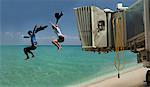 Couple jumping out of airport bridge onto seashore