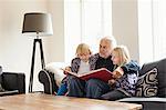 Grandfather reading book to grandchildren