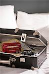 Open suitcase on bed with toy London bus and black cab