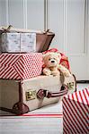 Suitcase filled with wrapped gifts and teddy bear