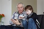 Senior man with grandson at home using digital tablet