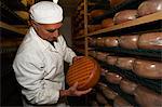 Senior man checking cheese round at farm factory