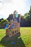 Two brothers and sister playing in garden with homemade pirate ship