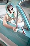 Woman in headscarf and white sunglasses in vintage convertible