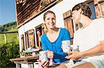 Two women drinking coffee outside chalet, Tyrol, Austria