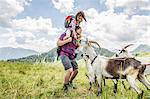 Man carrying daughter, looking at goats