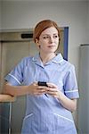 Female nurse with mobile phone outside hospital elevator