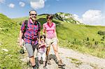 Parents and daughter walking on mountain track, Tyrol, Austria