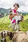 Young woman holding kid goat, Tyrol, Austria