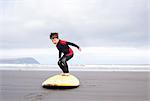 Boy practising on surfboard on beach