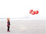 Portrait of boy on beach with red balloons