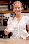 Portrait of young waitress holding coffee at kitchen counter