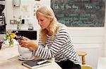 Young woman in cafe reading message mobile phone