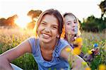 Portrait of girls sitting in field, one blowing bubbles