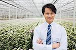 Man standing in front of rows of plants growing in greenhouse