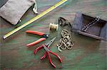 A tabletop with jewellery making equipment. Pliers, thread and a wooden tray, with measuring tape.