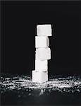 Stack of sugar cubes, balancing one on top the other, on black backdrop