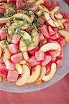 Organic prepared farm stand party food. Summer fruit salad of watermelon, peaches and mint.