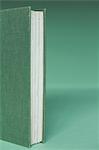 A hard cover book with a green cover, and white paper page edges, upright on a green background.