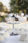 A table laid for a banquet or a wedding breakfast. White table cloth, cake stand, and table setting.