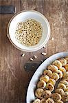 A white pottery bowl, full of dried corn kernels. A dish of baked pastries.