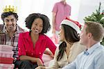 A woman wearing a red and white Father Christmas hat.  At home. A decorated Christmas tree.