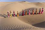 Women bear the responsibility of fetching water from the sparse wells within Rajasthan's vast Thar Desert. Trekking up the side of a sand dune, women expertly balance large clay water vessels atop their heads. Rajasthan, India