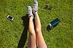 Young woman's legs on sunlit grass in park
