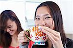 Two young women in kitchen having coffee break