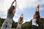 Three young women practicing yoga in park