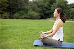 Young woman in park practicing yoga lotus position