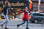 Young couple running along street, New York City, USA