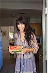 Young woman in doorway holding watermelon