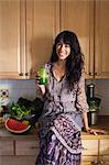 Young woman in kitchen with vegetable juice