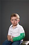 Portrait of sullen young boy with plaster cast on arm