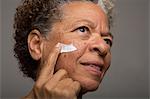 Close up studio portrait of senior woman applying face cream