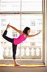 Woman doing dancer pose by window