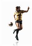 Studio shot of young female soccer player back kicking ball